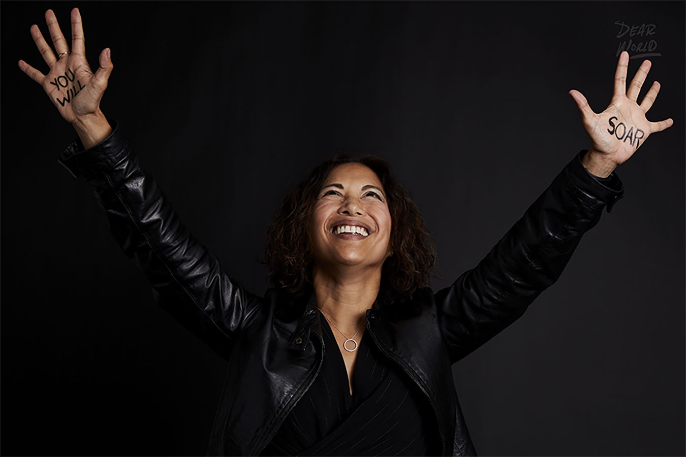 An image of Diana Cruz Solash, Vice President of Talent and ID&E at Vertex Pharmaceuticals, looking up and smiling with her hands in the air and the words “You will” written on her right hand and “Soar” written on her left hand.