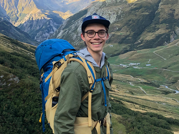 An image of Vertex Foundation Scholarship winner Tanner Eshleman wearing a hiking backpack with a mountain in the background